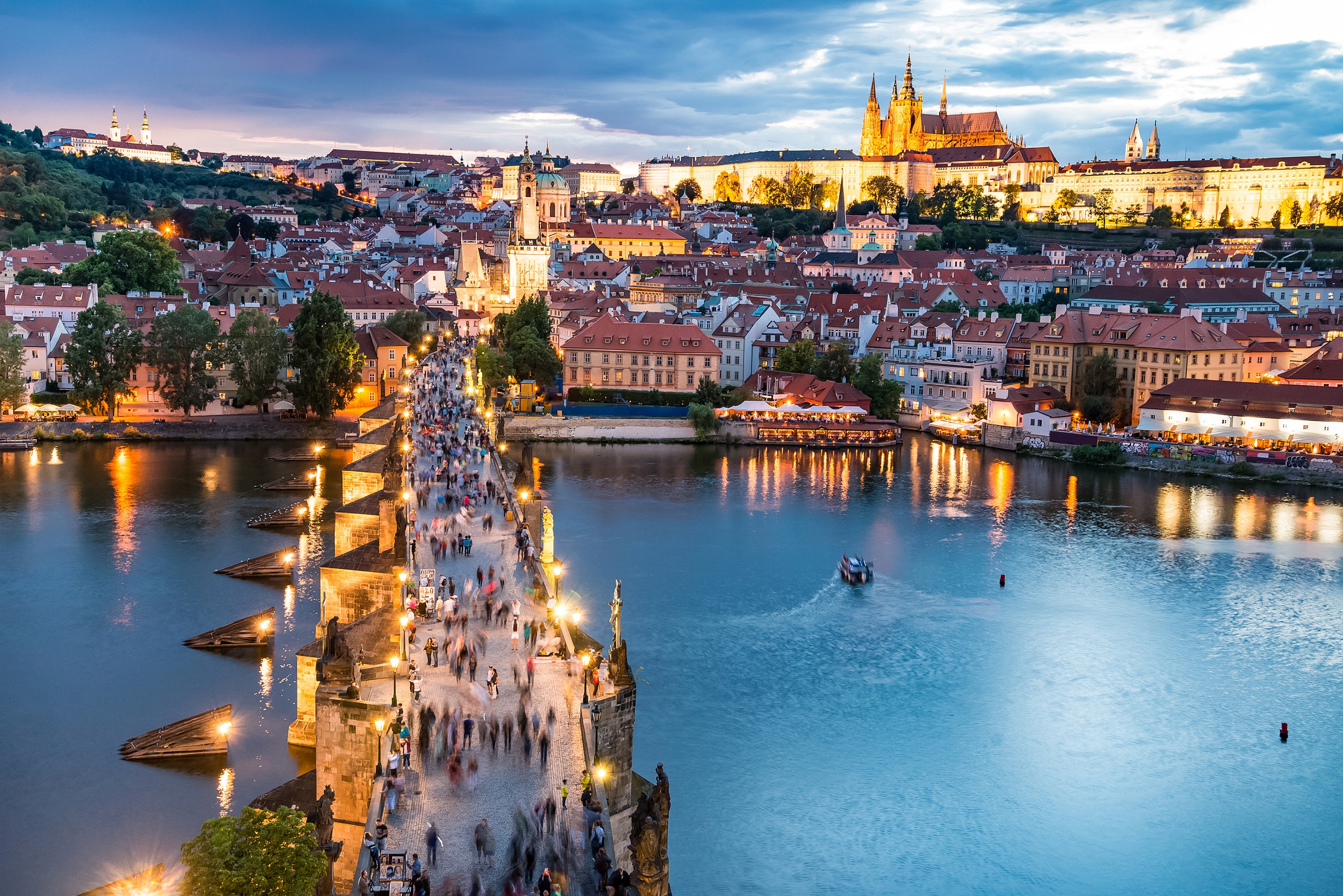 City view of Prague looking out across Charles Bridge lined with statues towards the hilltop castle
