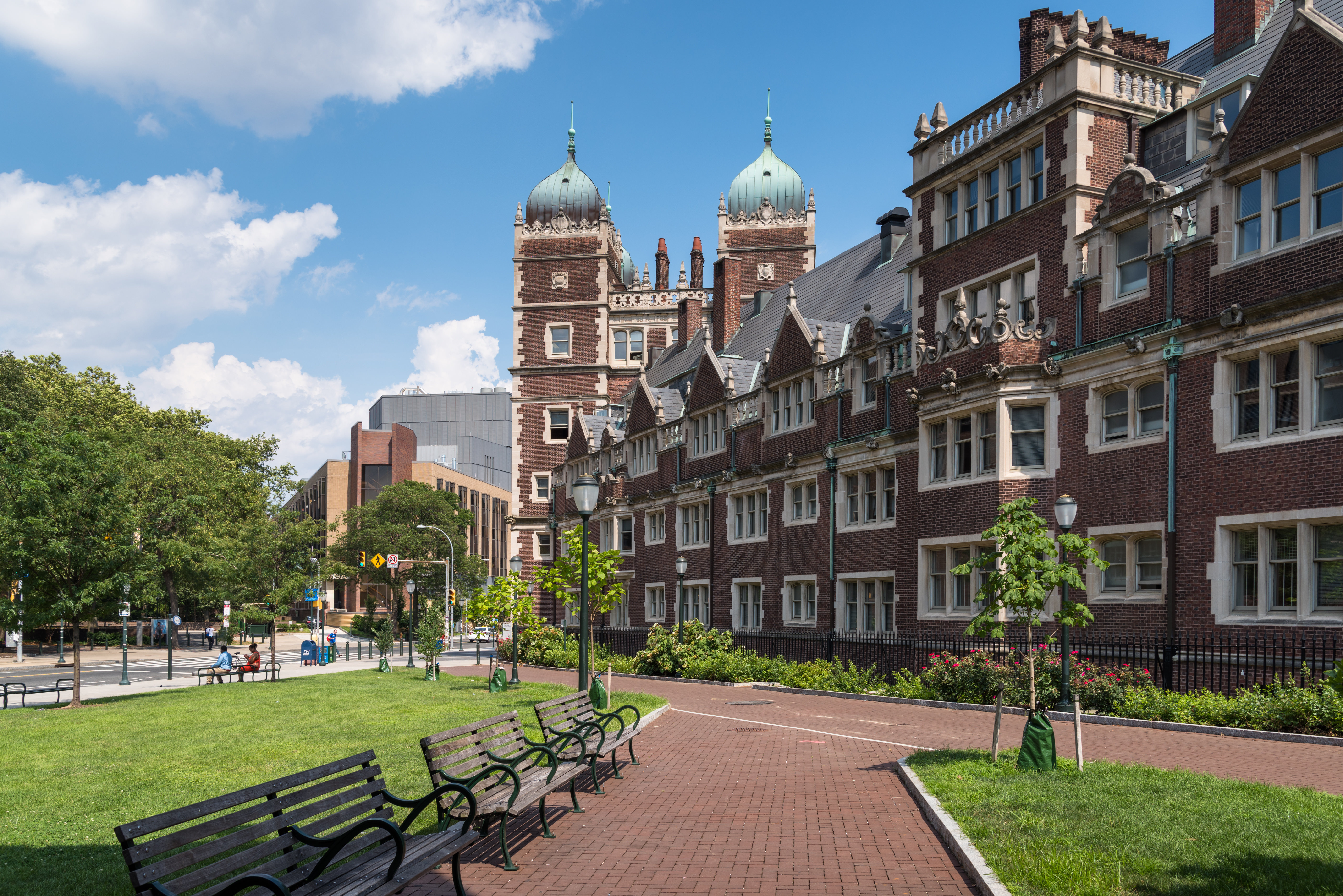 A large brick university building on the edge of a green campus