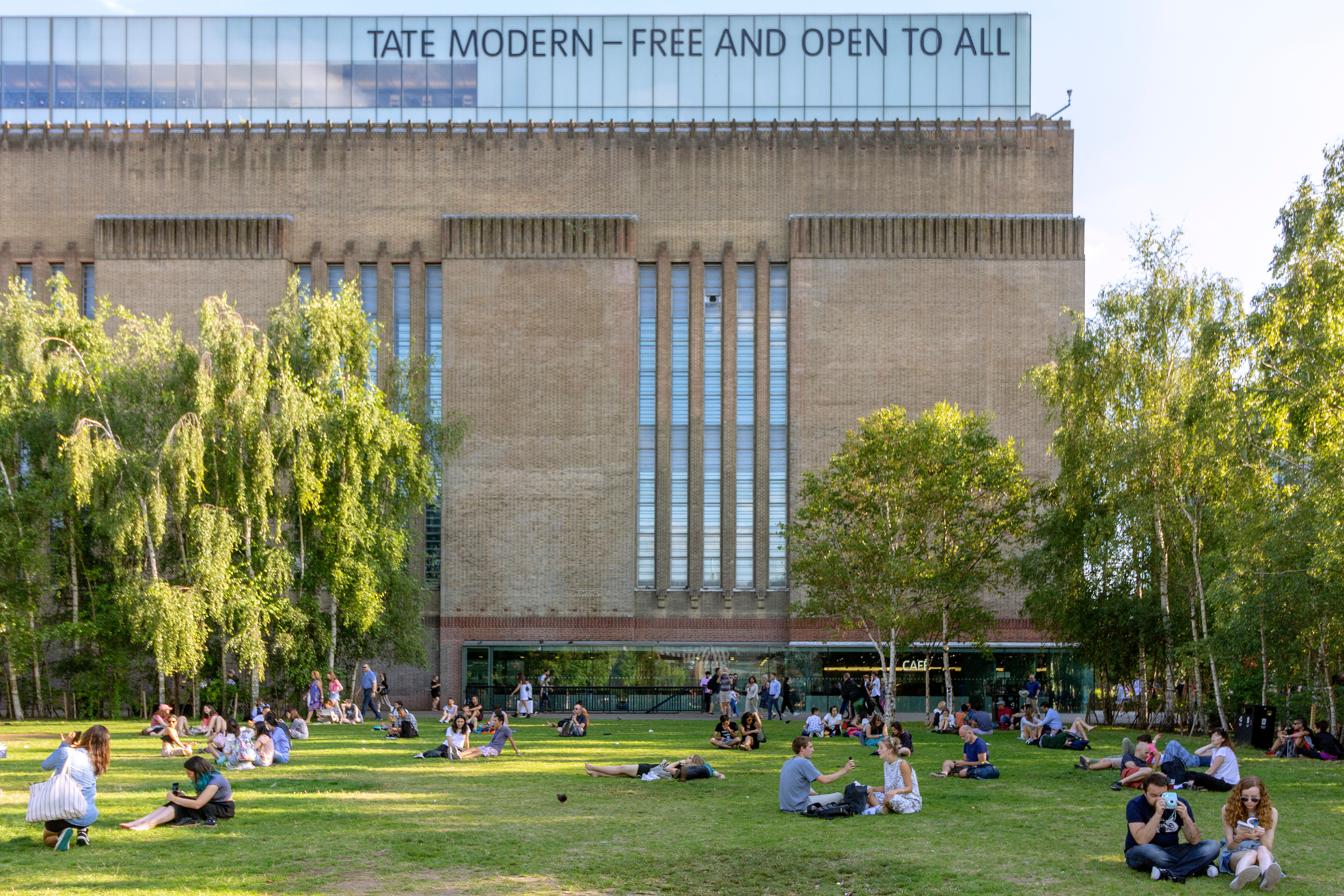 People seated on the grass outside the Tate Modern art gallery. 