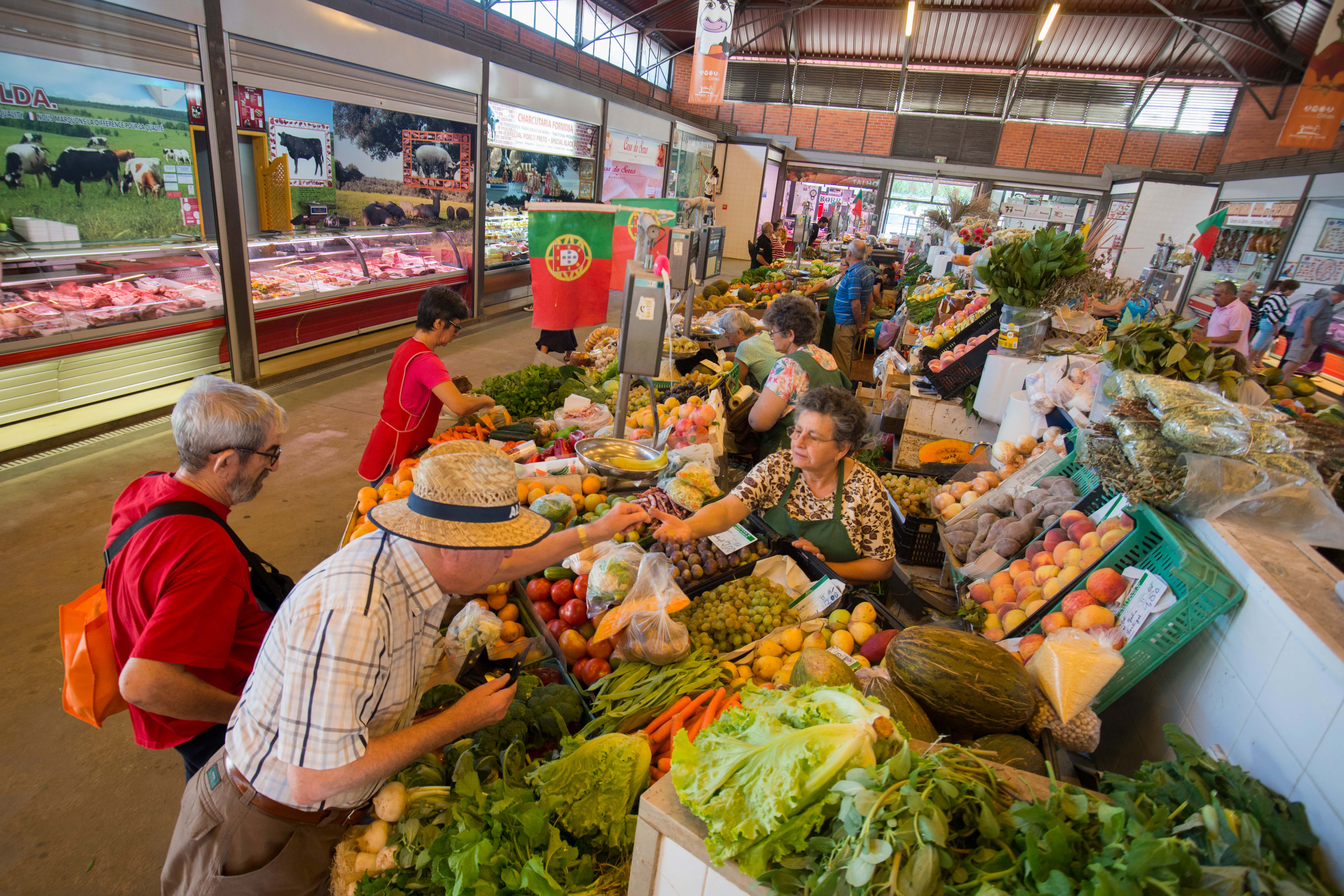 People purchase fruit and veg from a market trader in the Algarve, Portugal