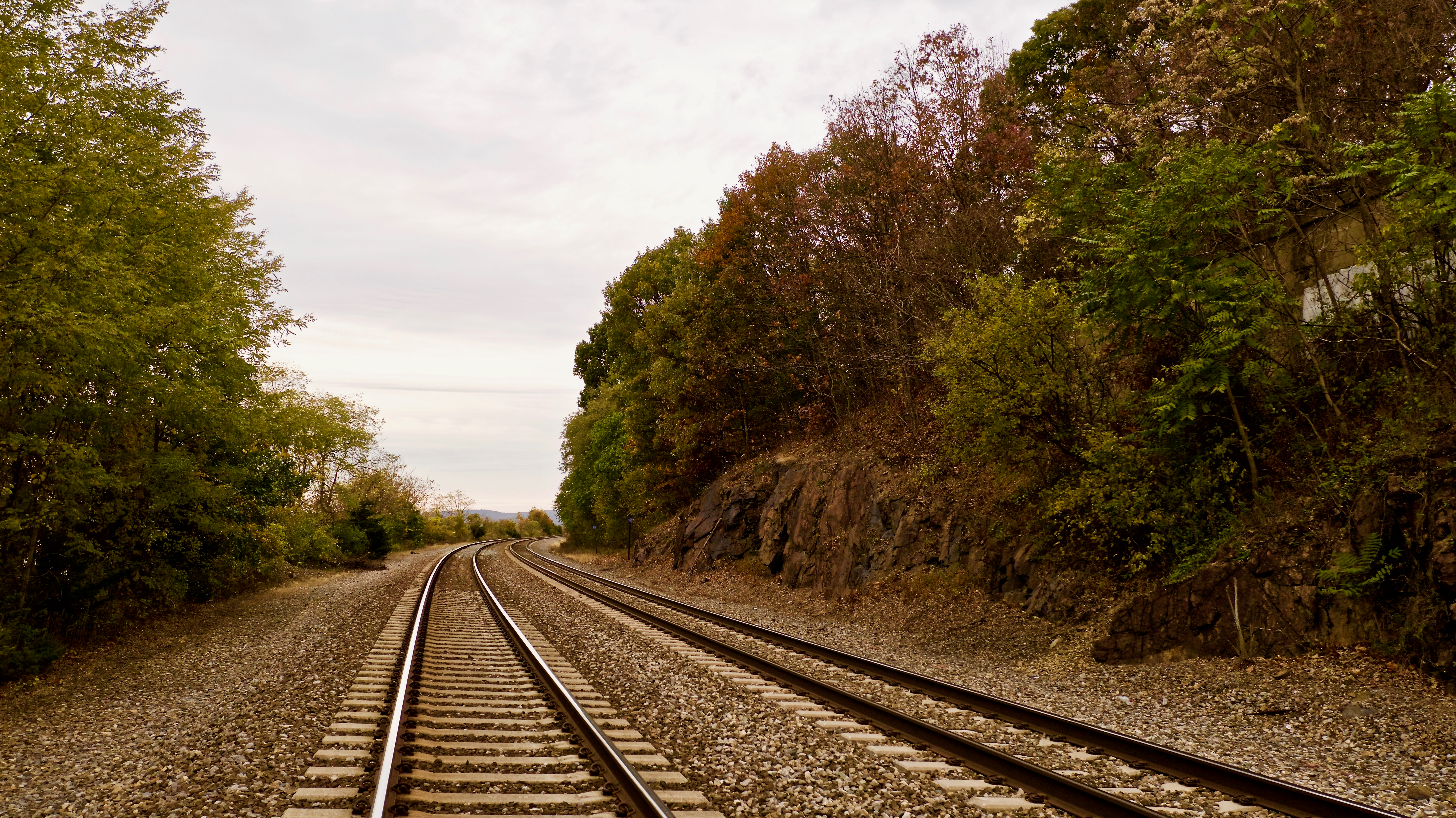 Shot of train tracks on a grey, cloudy day with trees on either side of the tracks in Beacon, Hudson Valley, New York, USA