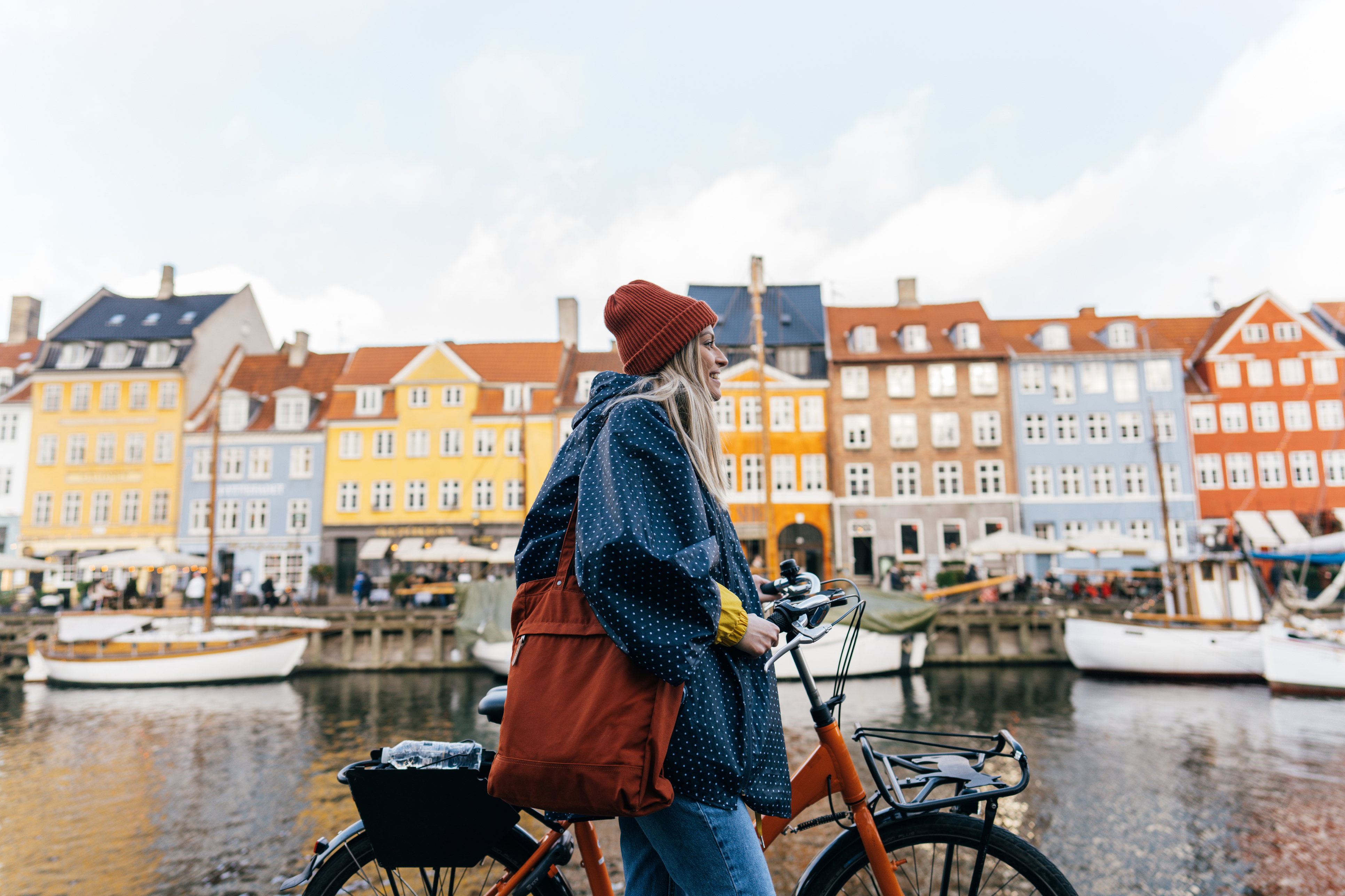 Copenhagen Photo of a young woman pulling the bike and walking down the street while exploring the famous tourist attraction in Copenhagen, Denmark