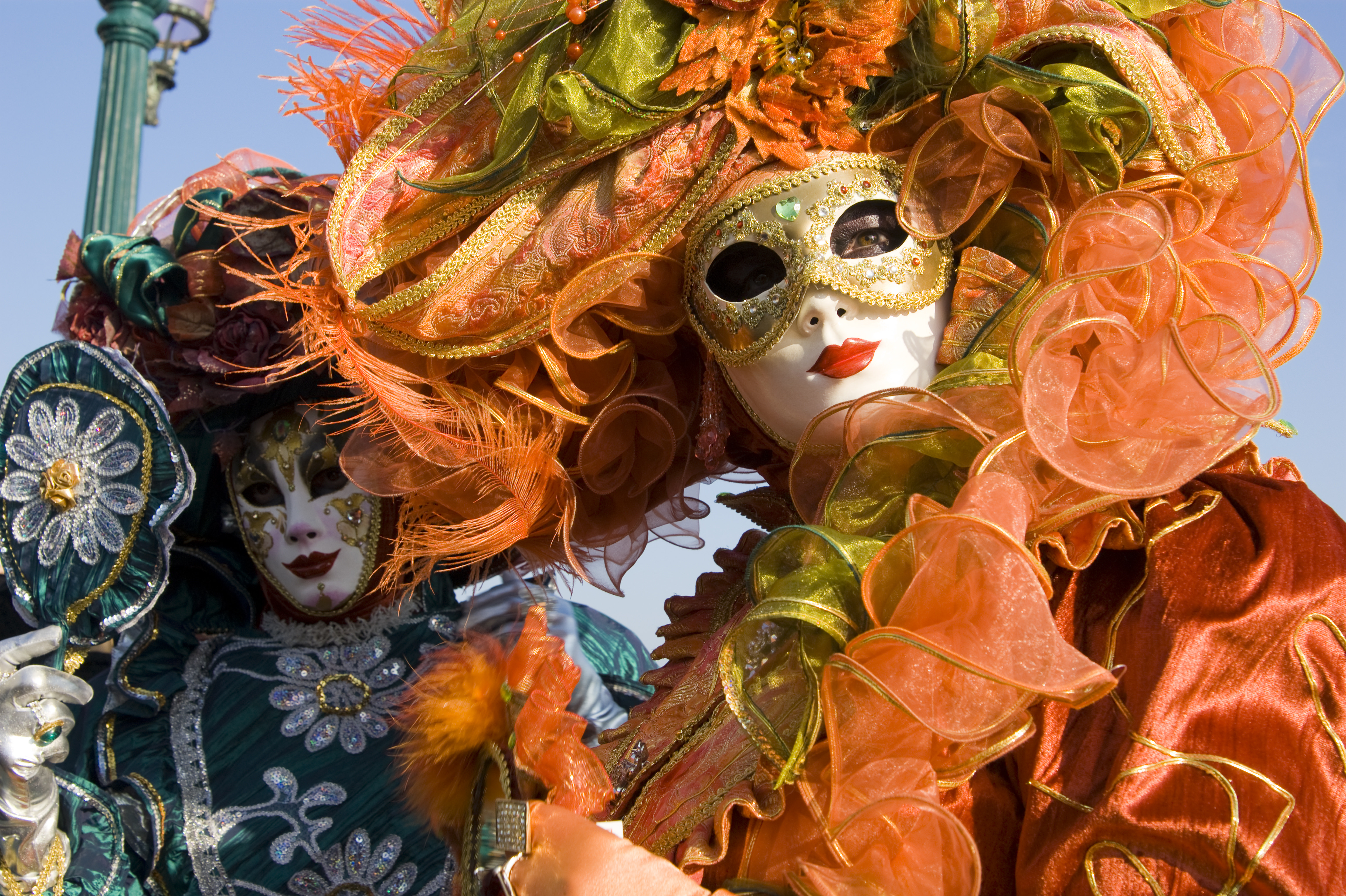 Venice People in masks and Venetians costumes look into the camera.