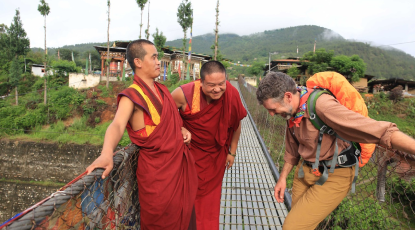 Two Buddhist monks and a trekker on a bridge in Bhutan. Two Buddhist monks and a trekker on a bridge in Bhutan.