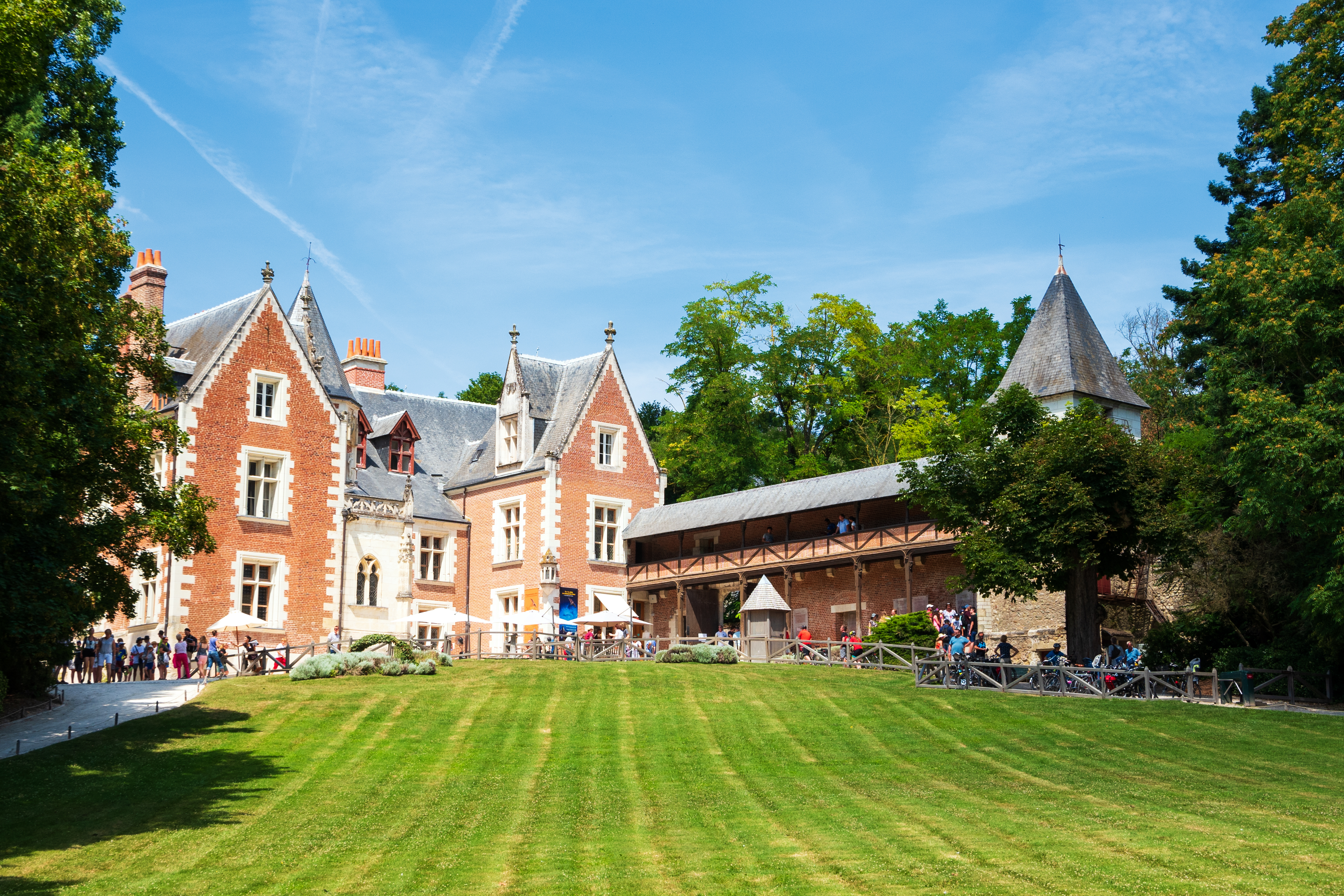 A large red-brick building with guests touring the vast landscaped grounds 