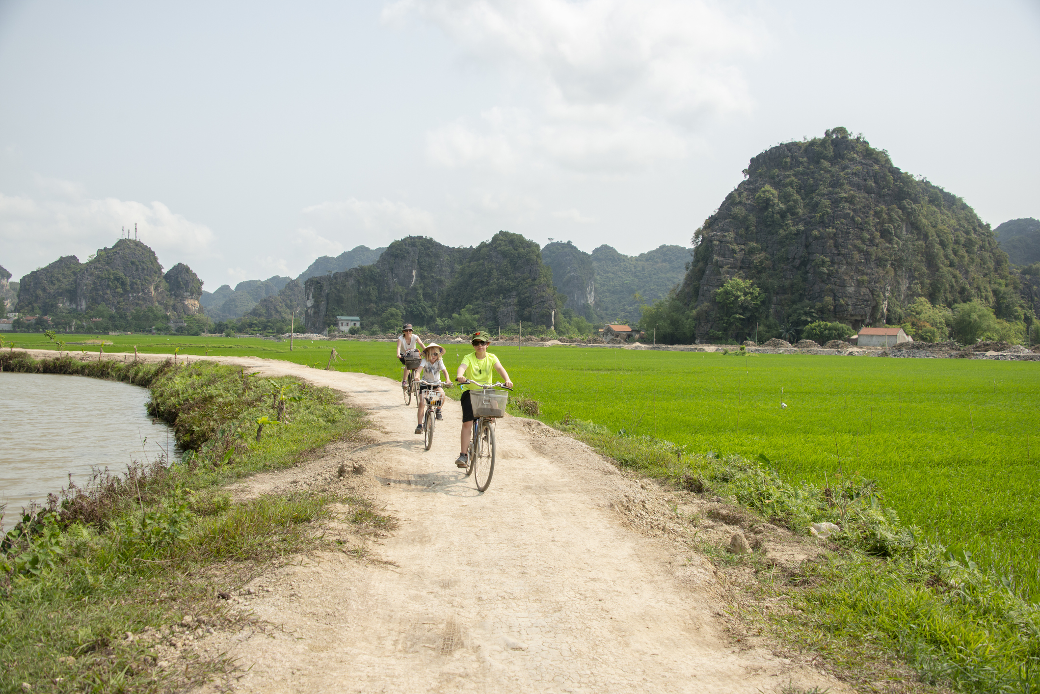 A family of three cycle along a trail through rocky outcrops