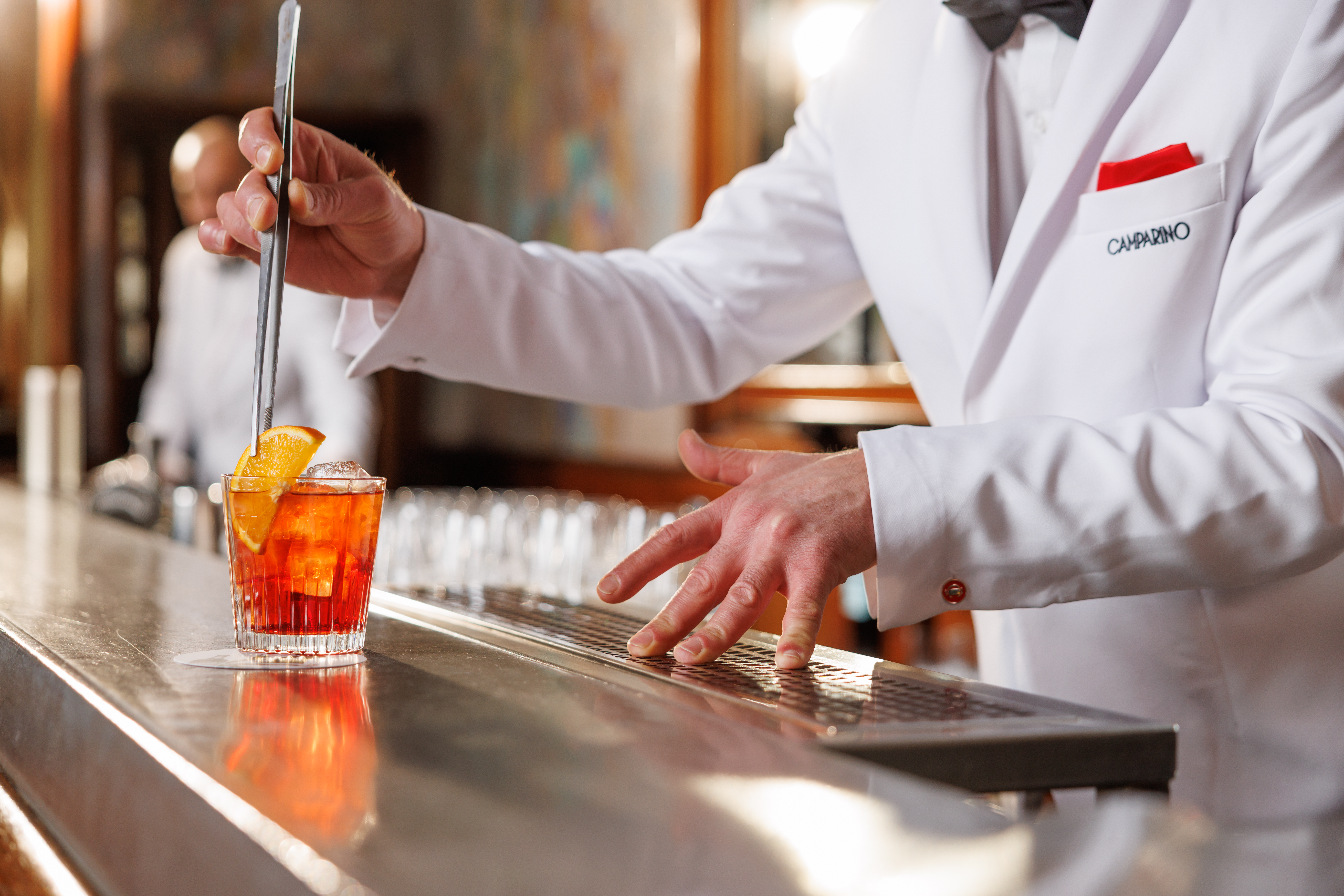 A waiter in sharp white suit stirs a Sbagliato cocktail at the Camparino cocktail bar in Galleria, Milan 