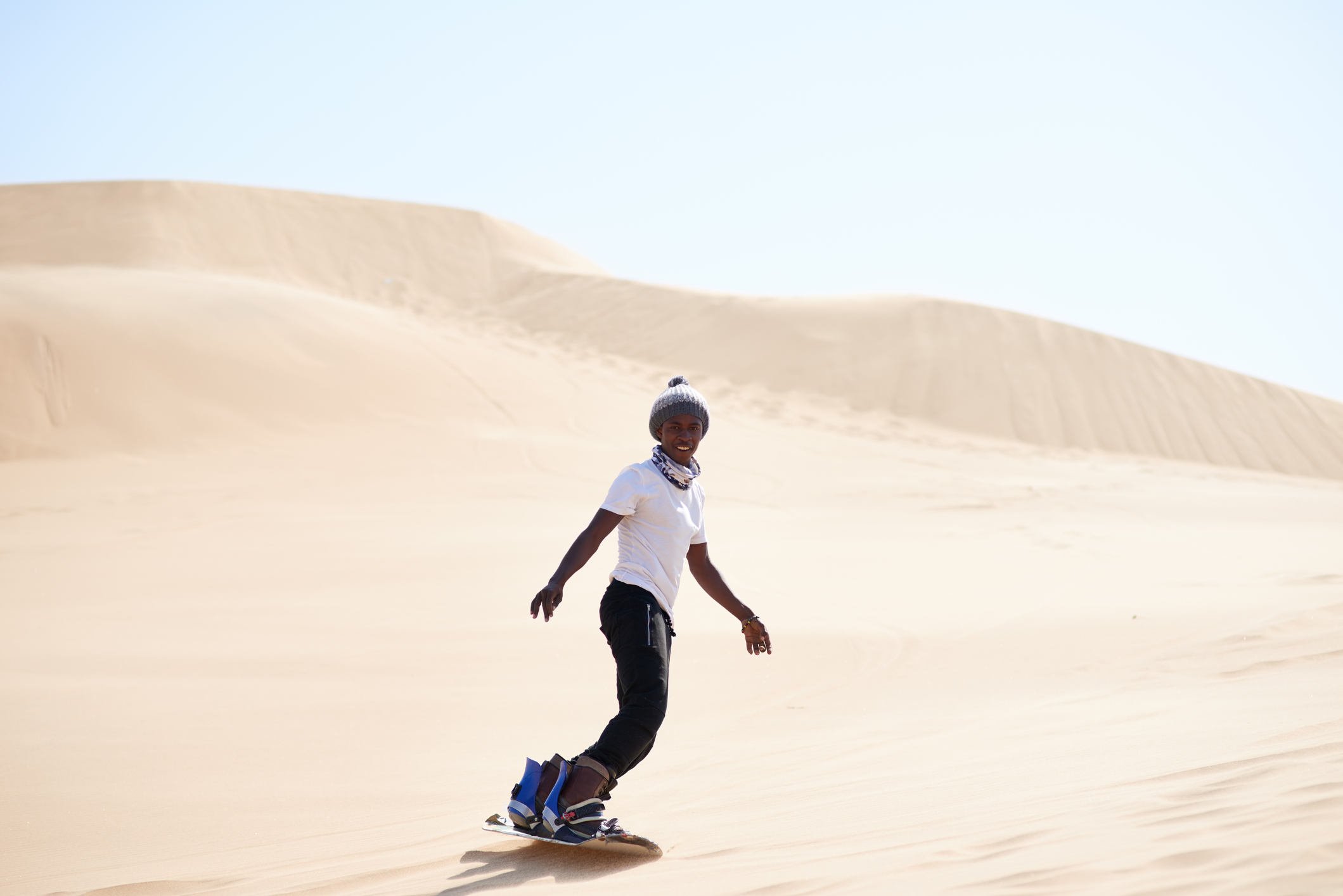 A young man sandboarding in the desert