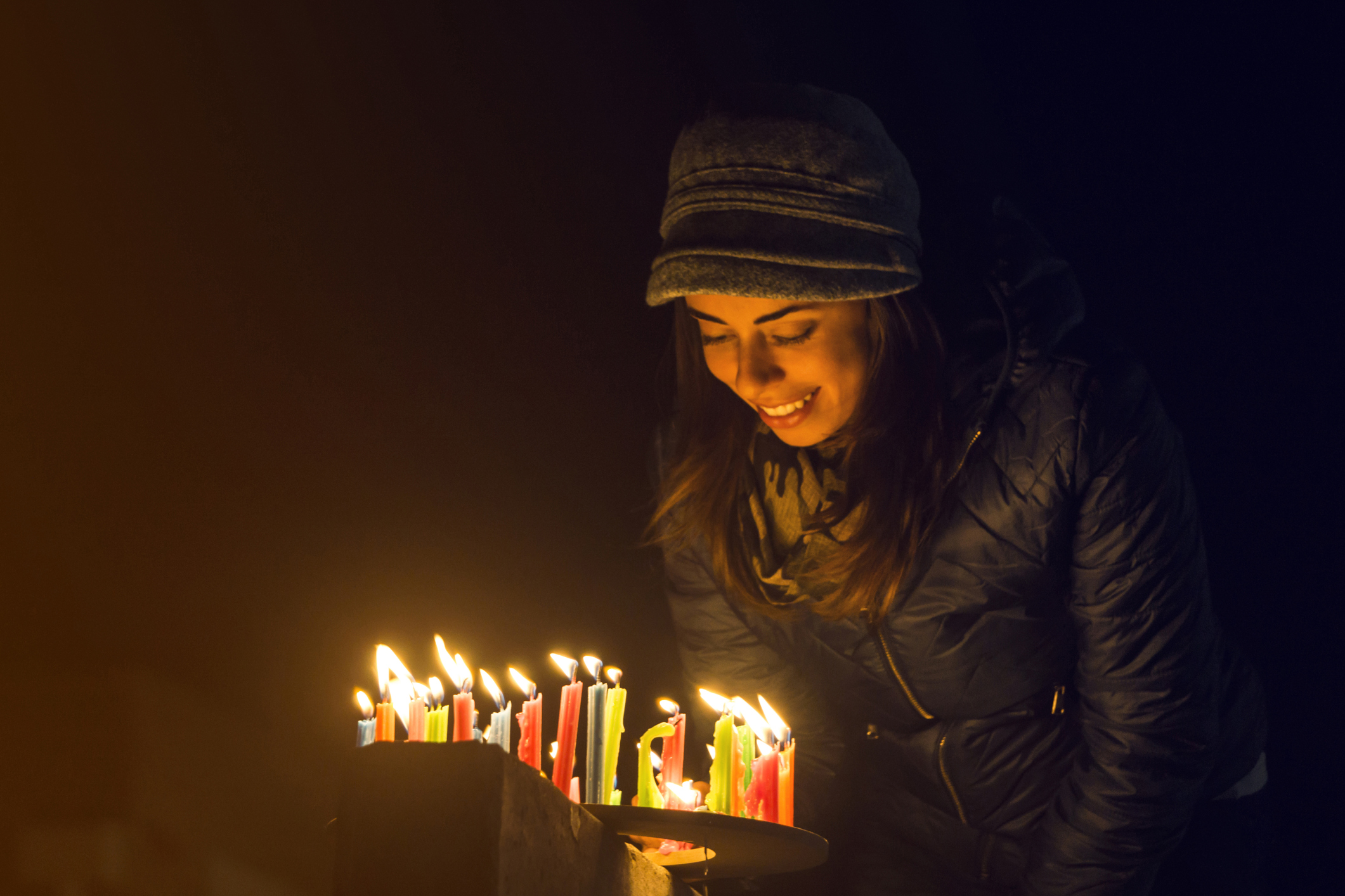 Happy Colombian woman lighting candles outdoors during the Noche de Velitas celebration that takes places on December 7 and marks the beginning of Christmastime