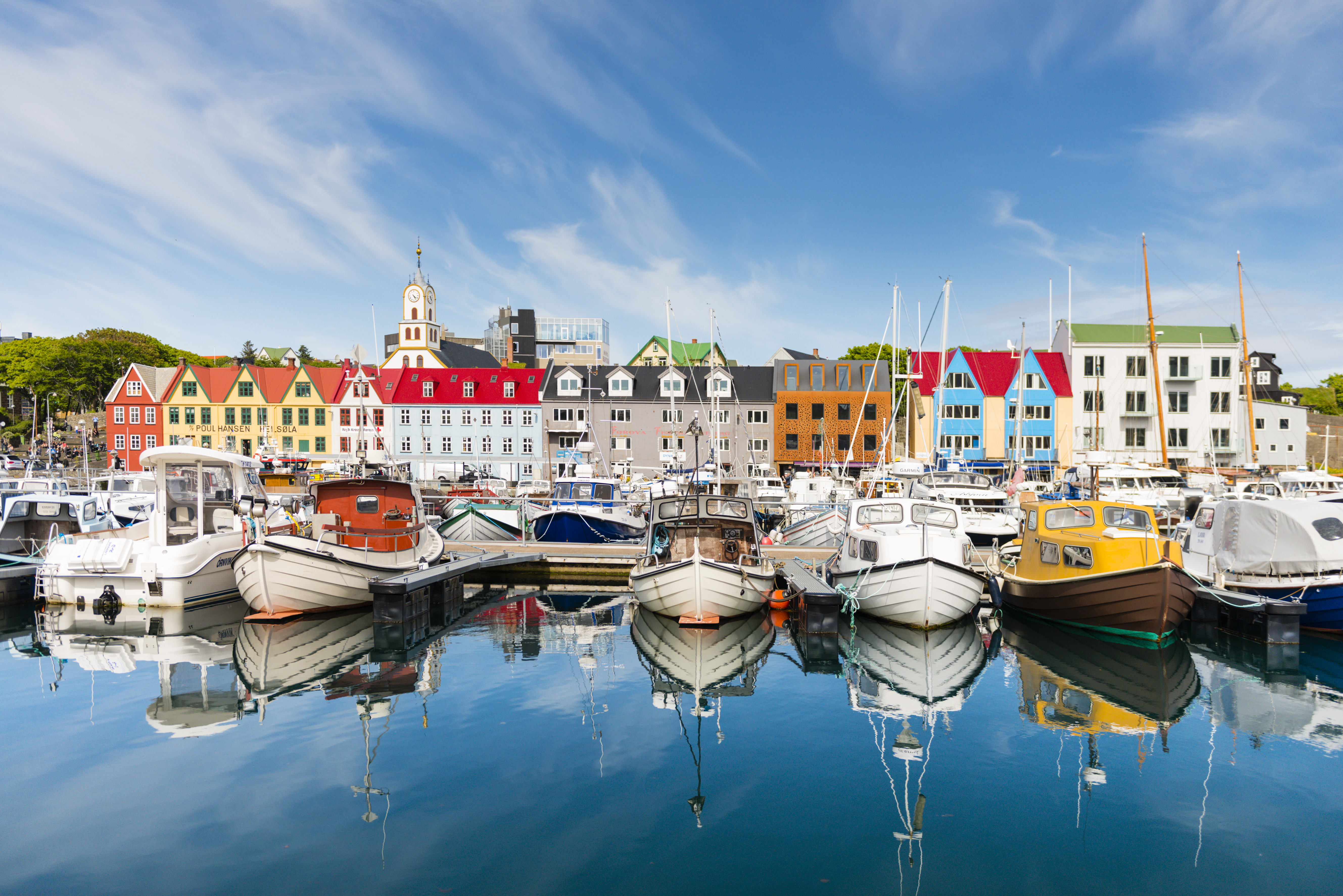 Many fishing boats are lined up in from of a row of colorful houses in the harbor at Tórshavn, the Faroe Islands 
