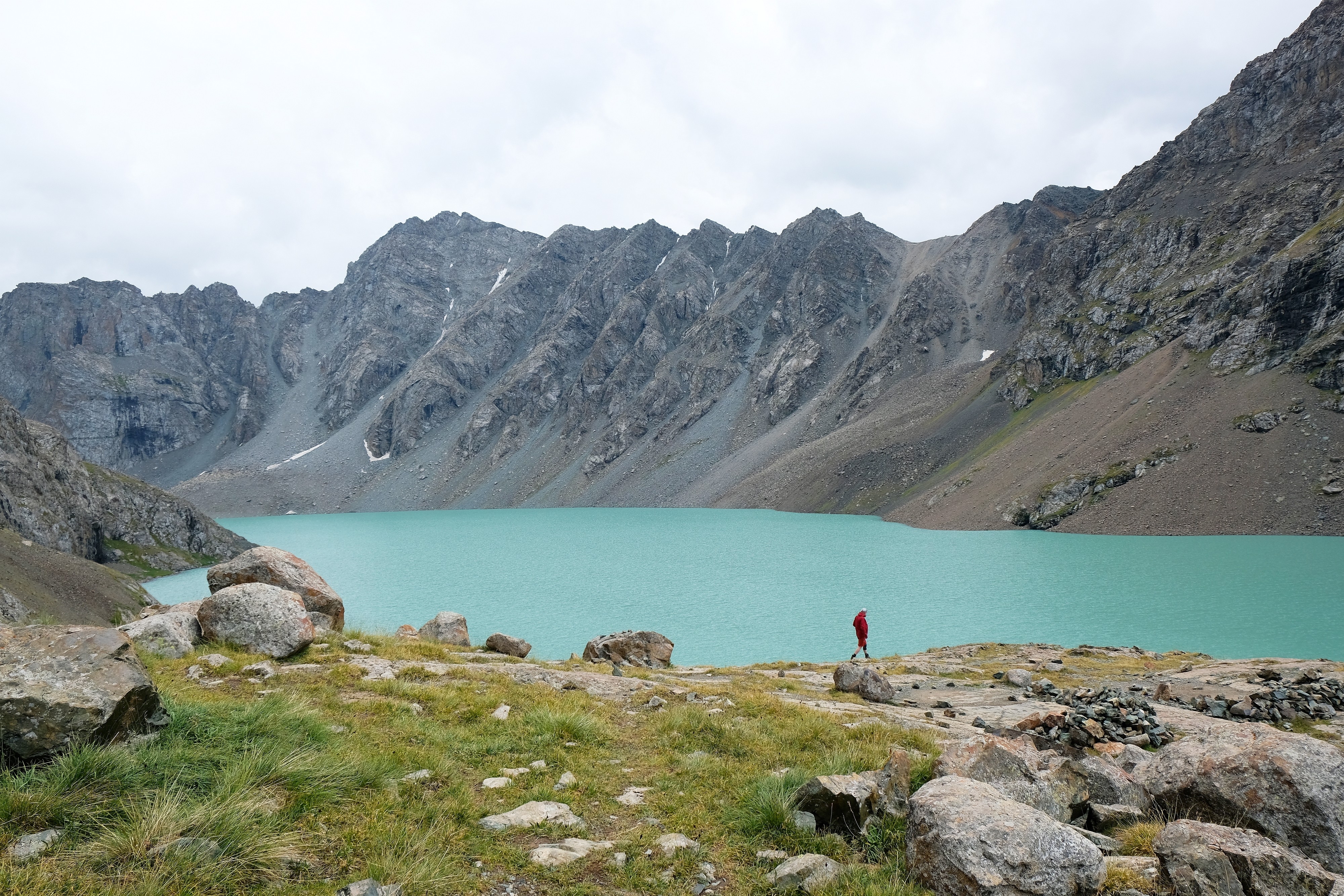 shutterstock2194455561.jpg A sole hiker walking near the edge of a turquoise alpine lake