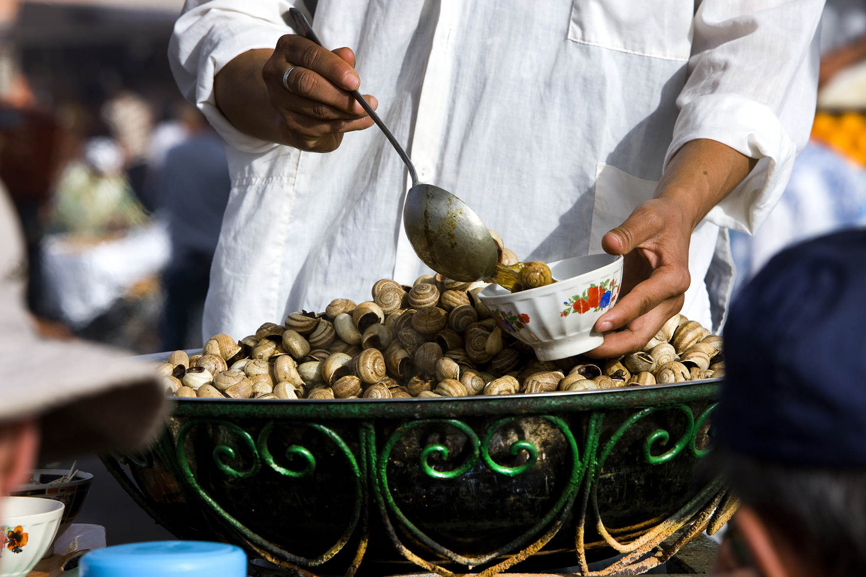 A man serves cooked snails in a bowl in a Marrakesh market. 